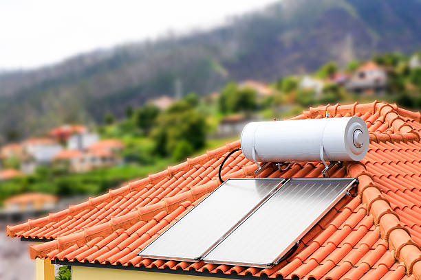 Water boiler with solar panels on roof of house in village of Madeira. In Portugal there is a lot of sun. On sunny days they can make enough green electricity to heat up the water in the tank. So they have warm tapping water for the shower. All the houses carry orange roof tiles.